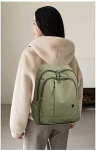 Olive green oxford nylon backpack shown from a rear view worn by a person