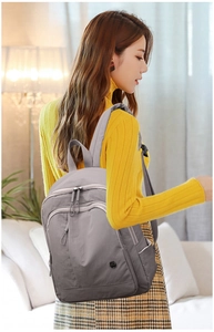 Detail of grey lightweight oxford backpack with multi-zipper compartments and metal logo