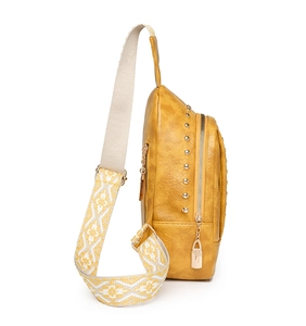 Détail d'un sac bandoulière jaune moutarde avec rivets métalliques et sangle à motifs