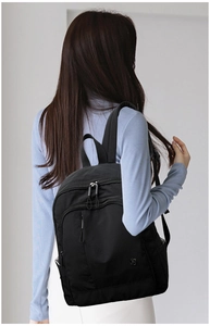 Close-up of lightweight black oxford cloth backpack with multiple zipper pockets and brand logo