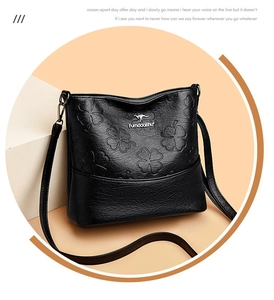 Détail du sac seau en cuir embossé noir avec motif trèfle et logo de marque kangourou