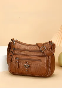 Detail view of brown soft leather crossbody bag with multiple pockets and heart buckle