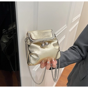 Détail d'un mini sac plissé doré métallique avec fermoir baiser et bandoulière chaîne