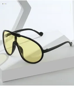 Detail einer Oversized-Aviator-Sonnenbrille mit gelben Gläsern auf weißem Sockel