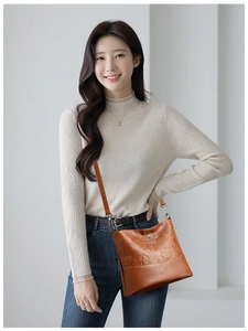 Détail du motif trèfle embossé sur un sac seau en cuir marron avec logo kangourou