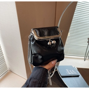 Gros plan d'un sac bandoulière noir brillant avec fermoir baiser et chaîne argent