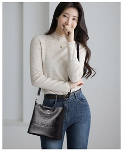 Détail du sac seau en cuir noir avec gaufrage trèfle et logo kangourou argenté brillant