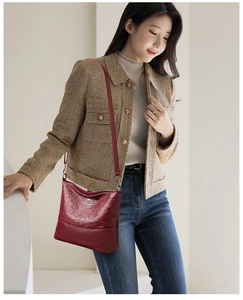 Détail du sac seau bordeaux en cuir gaufré porté par un mannequin montrant la texture