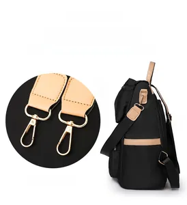Detail view of the black nylon backpack showing a detachable gold hook and side pocket