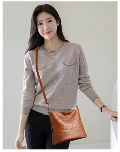 Détail du motif trèfle embossé et logo en métal sur sac seau en cuir souple marron