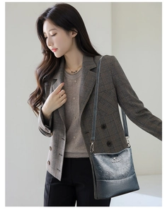 Détail du sac seau gris foncé en cuir souple avec motifs trèfles gaufrés et logo en métal