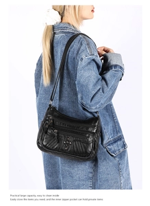 Detailed side view of black soft leather crossbody bag with multiple zip pockets and heart clasp