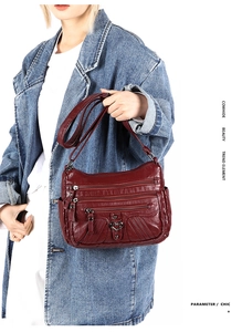 Detail of dark red cowhide shoulder bag with multi-zipper layers and heart hardware