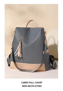 Detail of dark grey nylon backpack featuring beige contrast base and tassel zipper detail