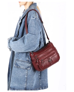 Detail of wine red multi-pocket crossbody bag with adjustable strap and heart hardware