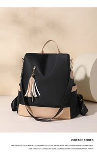 Detail of color-block backpack with leather trim, vertical zipper and tassel charm