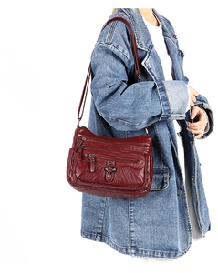 Detail of burgundy leather shoulder bag with multiple zip pockets and heart metal buckle