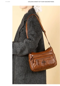 Detail of vintage brown multi-pocket crossbody bag with heart buckles on grey coat