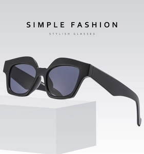 Close-up of thick black geometric frame sunglasses with dark smoke lenses on a white base