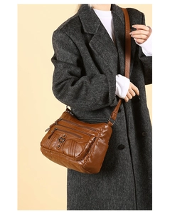 Detail view of brown soft leather crossbody bag with multiple zippers and heart hardware