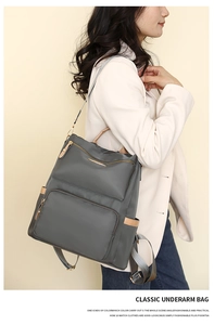 Detail of grey travel backpack with brown faux leather trim and multiple zipper pockets