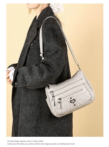 Detail view of a grey multi-zippered crossbody bag with a heart-shaped metal buckle