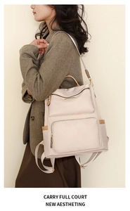Close-up of beige nylon backpack with gold zippers and multi-pocket functional design