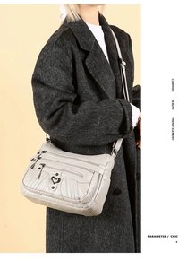 Detail of grey cowhide crossbody bag with multi-zipper pockets and heart metal buckle