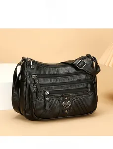 Detail view of black multi-pocket soft leather crossbody bag with heart-shaped metal decor