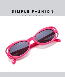 Detail of rose pink oval sunglasses with hollow frame design and dark gray UV lenses