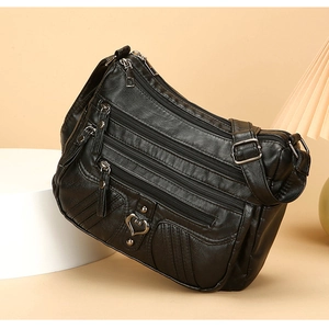 Detail view of the black multi-zippered crossbody bag with a heart-shaped metal buckle