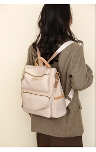 Close-up of lightweight nylon backpack with brown leather trim and gold hardware accents