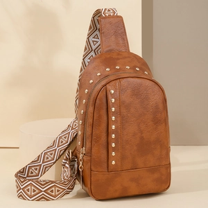 Sac de poitrine en cuir marron clouté avec bandoulière géométrique sur socle minimaliste