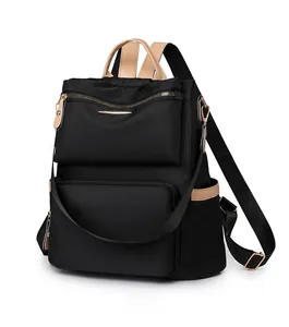 Close-up of black waterproof nylon backpack with brown leather trim and gold zippers