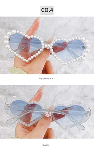 Détail de lunettes de soleil en forme de cœur avec perles, verres bleu clair et strass