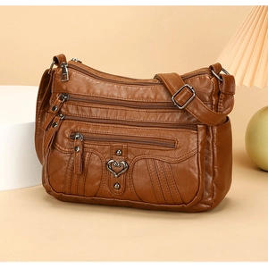 Detail of vintage brown soft leather crossbody bag with multiple zippers and heart hardware
