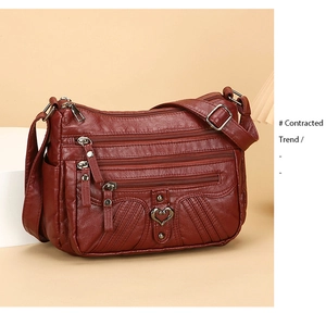 Detail of burgundy crossbody bag with multiple zip pockets and textured faux leather