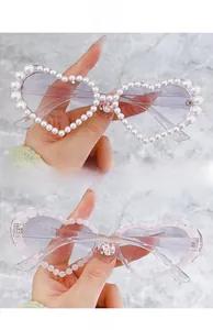 Détail de lunettes de soleil en cœur avec bordure de perles et strass rose sur monture claire