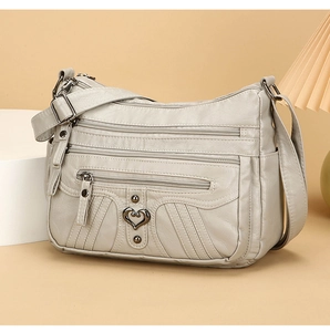 Detail view of grey PU leather bag with multi-zipper pockets and heart metal buckle