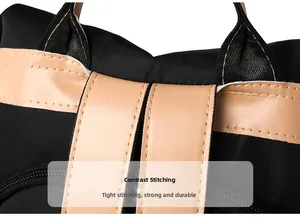 Close-up of contrast stitching on light brown leather handle of black nylon backpack