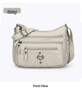 Front view of a grey multi-pocket crossbody bag with soft leather and heart detail