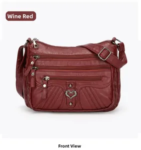 Front view of a wine red multi-pocket shoulder bag with heart-shaped metal buckle details