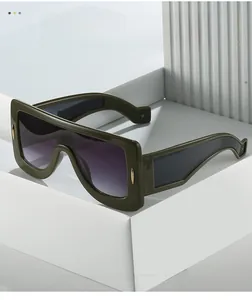 Detail view of futuristic green oversized sunglasses with thick frames and purple gradient lenses