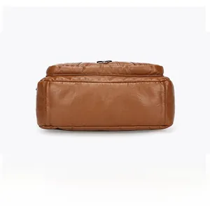 Detail view of the flat wide bottom on a brown leather crossbody bag with neat stitching