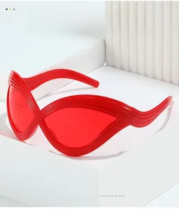 Close-up of red cat eye sunglasses with wavy frames on a minimalist white pedestal