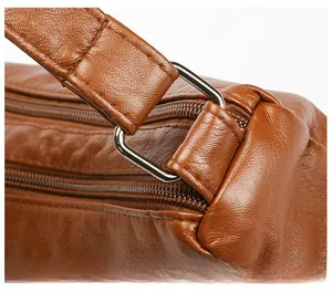 Detail of silver D-ring hardware and precise stitching on brown faux leather bag