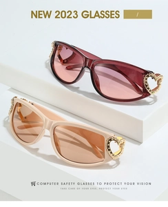 Detail of Y2K sunglasses temple with gold heart ornament on white platform