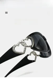 Detail of silver interlocking hearts on black Y2K sunglasses temple with smoky lenses