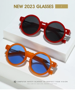 Close-up of retro round frame sunglasses in red and orange on white geometric blocks