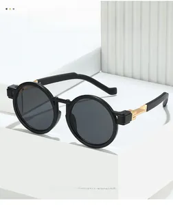Detail of round vintage sunglasses with gold hinges on architectural white background
